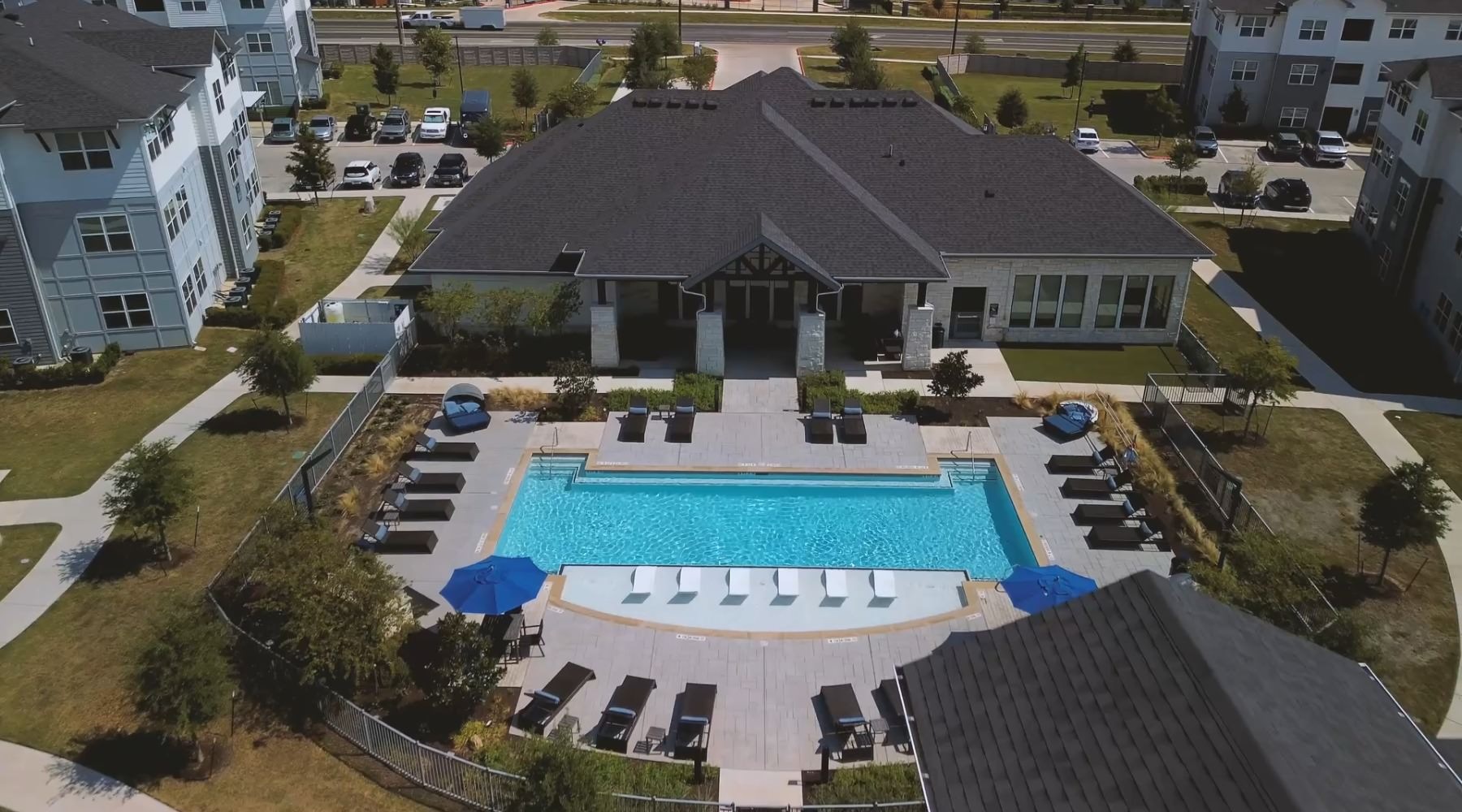 Access to resident only features resort style pool with seating with a building behind it
